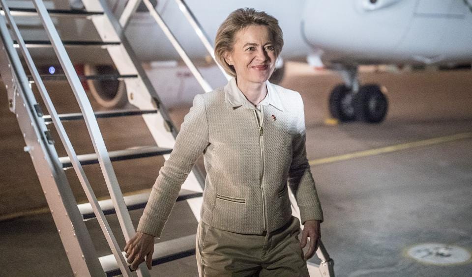 Il leader della Commissione europea a piedi di un aeroplano, vestito di abbronzatura e sorridente.